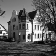 Vila von 1899 mit Rundgeibel links und Stufengiebel rechts, dazwischen ein kleiner Turm. Ober ist rot gestrichenes Fachwerk zu sehen